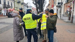 policjanci rozdają elementy odblaskowe pieszym.