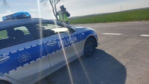 policjant dokonujący pomiaru prędkości na drodze.