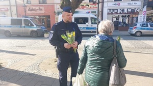 policjant wręcza kwiatek mieszkance Kutna.