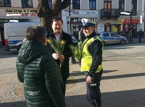 policjant wręcza kwiatek mieszkance Kutna.