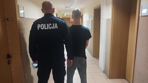 policjant prowadzący zatrzymanego mężczyznę.