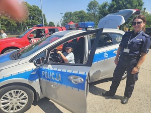 radiowóz policyjny i dzieci z policjantką.