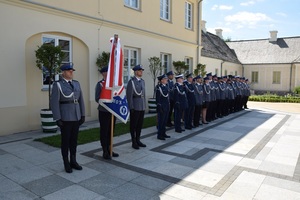 mianowani policjanci stojacy w szyku oraz poczet sztandarowy.