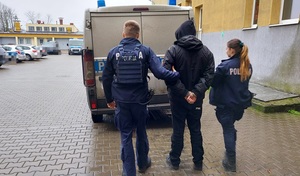 policjanci prowadzą zatrzymanego mężczyznę.