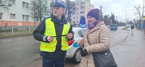 Policjant przekazuje odblaski mieszkańcom.