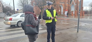 Policjant przekazuje odblaski mieszkańcom.