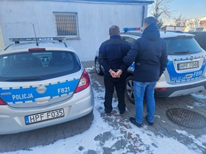 policjant prowadzacy zatrzymanego mężczyznę.