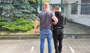 policjant prowadzi zatrzymanego obcokrajowca.