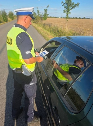 policjant daje kierującemu ulotkę &quot;mistrzu zwolnij&quot;.