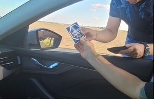 policjant daje kierującemu ulotkę &quot;mistrzu zwolnij&quot;.