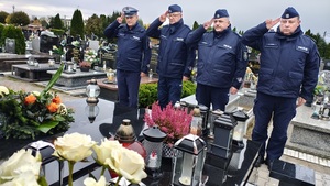 policjanci oddaja honor przy grobie zmarłego funkcjonariusza.