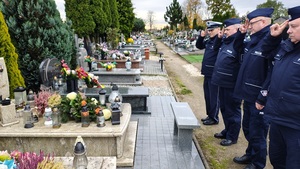 policjanci oddaja honor przy grobie zmarłego funkcjonariusza.