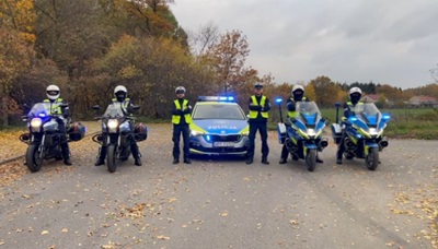 policjanci na morocyklach oraz przy radiowozie policyjnym.