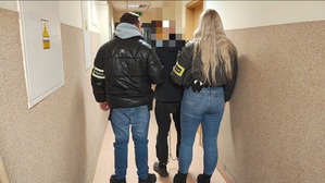 policjanci prowadzą zatrzymanego mężczyznę.