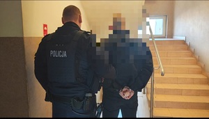 policjant prowadzi zatrzymanego mężczyznę.
