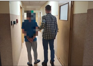 policjant prowadzi zatrzymanego mężczyznę.