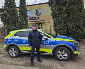 dzielnicowy aspirant Jarosław Rączkiewicz przy radiowozie.