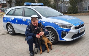 policjant wraz z pieskiem - Walutą na tle radiowozu .