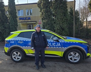 dzielnicowy z Krośniewic na tle radiowozu.