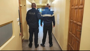 policjant prowadzi zatrzymanego mężczyznę.