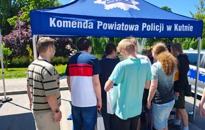 policjanci na stoisku promocyjnym wraz z zainteresowanymi osobami służbą w policji.