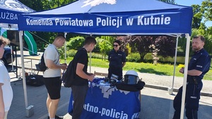 policjanci na stoisku promocyjnym wraz z zainteresowanymi osobami służbą w policji.