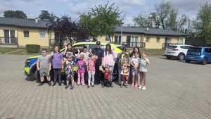 dzieci z półkoloni z policjantką przy radiowozie.