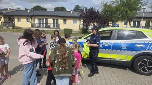 dzieci z półkoloni z policjantką przy radiowozie.