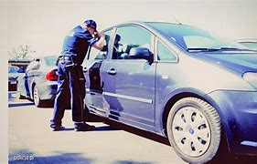 policjant zaglądający przez okno zamkniętego pojazdu.