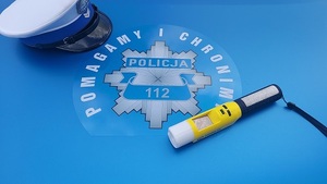 na masce samochodu słuzbowego leży policyjna czapka Wydziału Ruchu drogowego i alkomat.