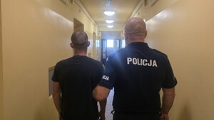 policjant prowadzi zatrzymanego.