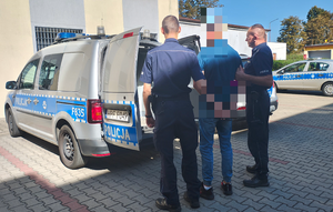 policjanci prowadzą zatrzymanego mężczyznę.