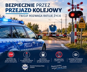 policyjny radiowóz na tle przejazdu kolejowego.